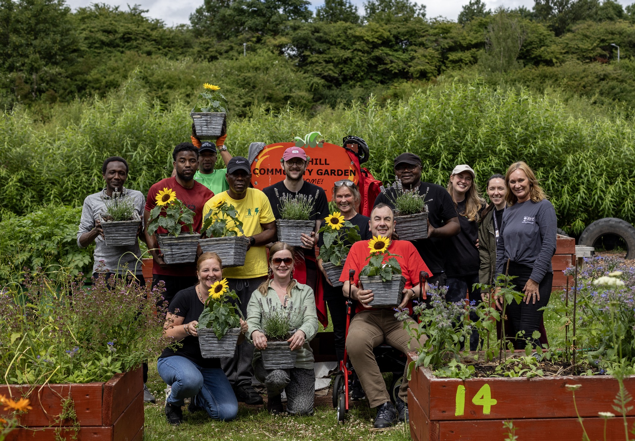 Cranhill community garden with a group of people in the foreground holding plants