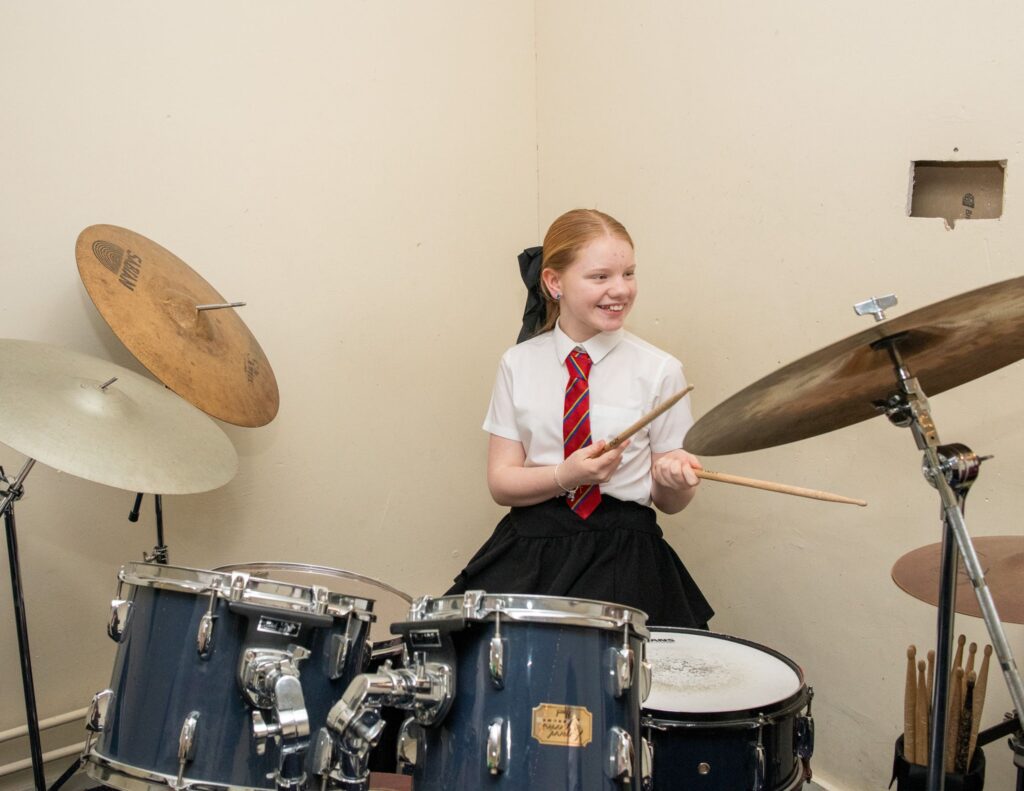 A child in a school uniform is playing drums
