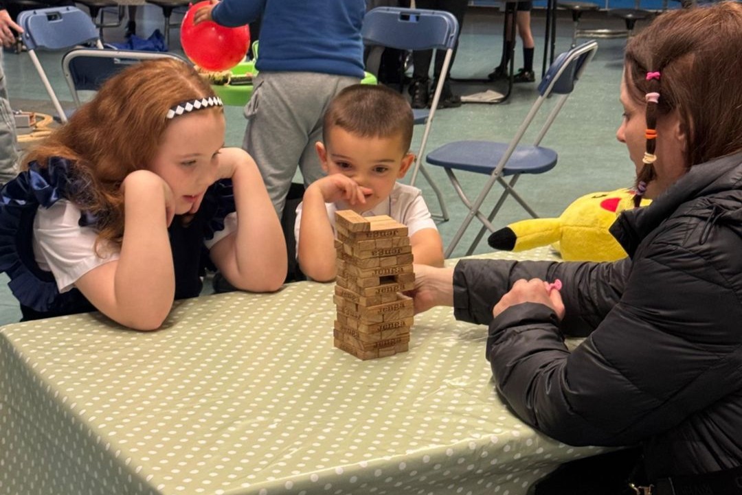Young boy looks at the camera as children converse at a table