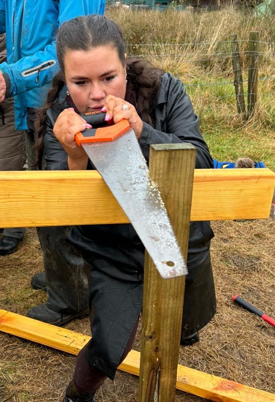 Kirsty sawing a fence